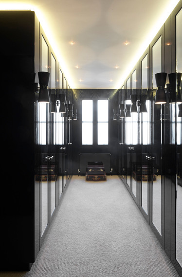 Example of a mid-sized minimalist gender-neutral carpeted walk-in closet design in London with flat-panel cabinets and black cabinets
