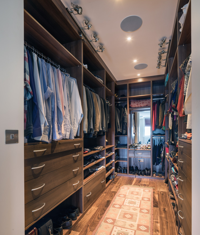 Diseño de armario vestidor unisex tradicional renovado con armarios abiertos, puertas de armario de madera en tonos medios, suelo de madera oscura y suelo marrón