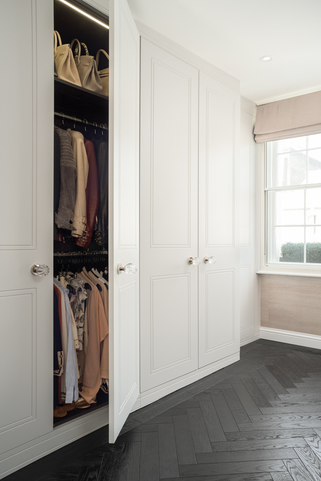 Design ideas for a large traditional standard wardrobe in London with dark hardwood flooring and black floors.