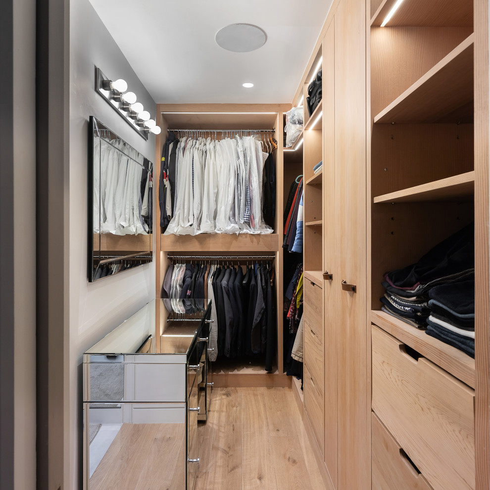 Design ideas for a contemporary walk-in wardrobe for men in London with flat-panel cabinets, light wood cabinets, light hardwood flooring, beige floors and feature lighting.