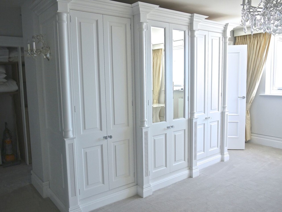 Cette photo montre un dressing et rangement chic neutre avec un placard avec porte à panneau surélevé, des portes de placard blanches et moquette.