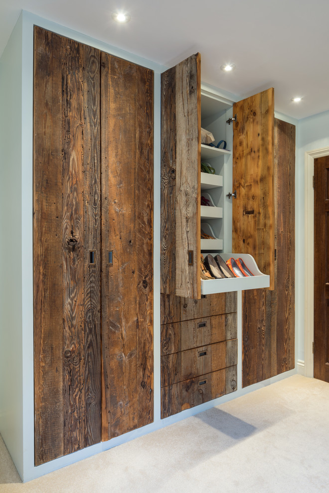 Ejemplo de armario unisex tradicional de tamaño medio con armarios con paneles lisos, puertas de armario de madera oscura, moqueta y suelo beige