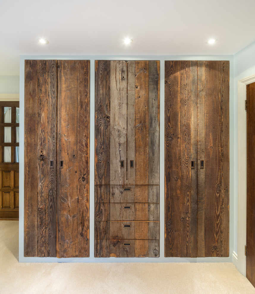 Idee per un armadio o armadio a muro unisex tradizionale di medie dimensioni con ante lisce, ante in legno scuro, moquette e pavimento beige