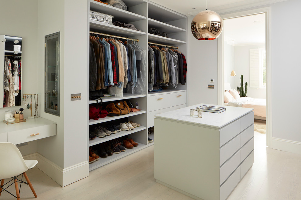 Diseño de vestidor unisex actual grande con armarios con paneles lisos, puertas de armario blancas, suelo de madera clara y suelo beige