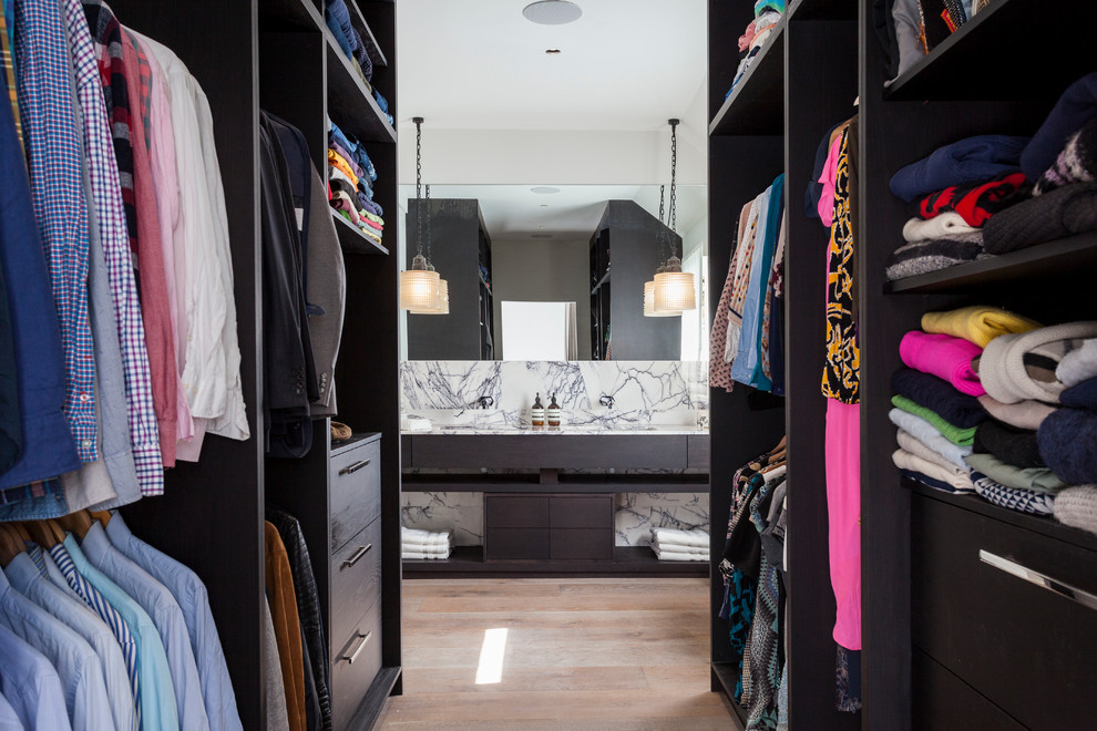 Mid-sized trendy closet photo in London with dark wood cabinets