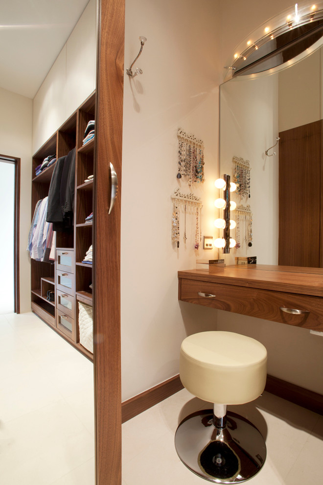 Medium sized contemporary gender neutral dressing room in London with dark wood cabinets.