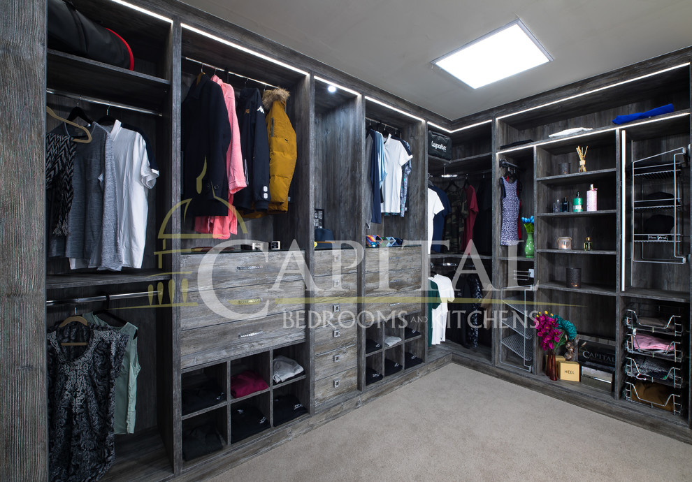 Inspiration for a medium sized traditional gender neutral walk-in wardrobe in London with open cabinets, medium wood cabinets, carpet and beige floors.