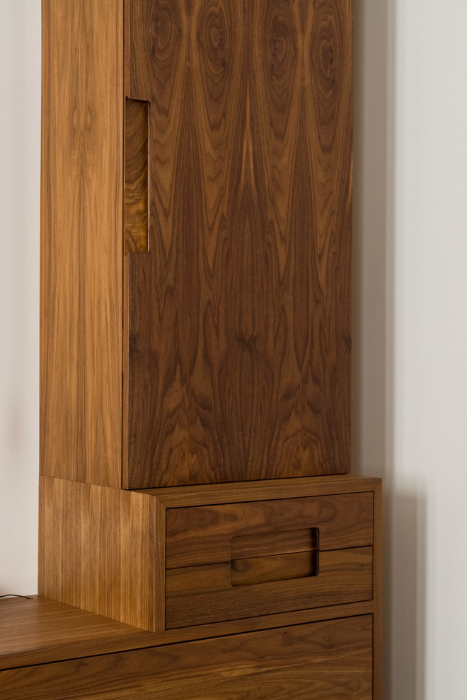 Diseño de armario unisex actual grande con armarios con paneles lisos, puertas de armario de madera en tonos medios y suelo de madera oscura
