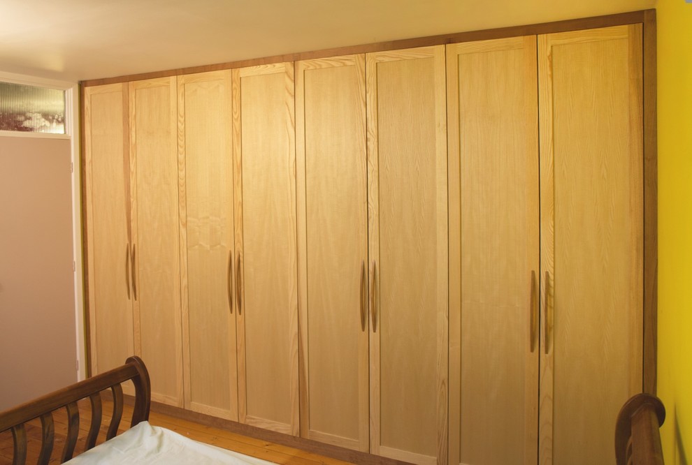 Foto de armario unisex con armarios con paneles empotrados y puertas de armario de madera clara