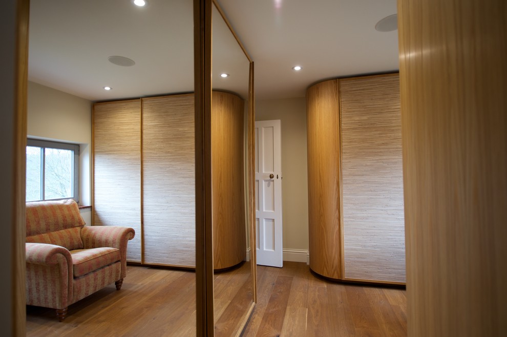 Modelo de vestidor unisex bohemio de tamaño medio con puertas de armario de madera en tonos medios, suelo de madera en tonos medios, suelo marrón y armarios con paneles lisos