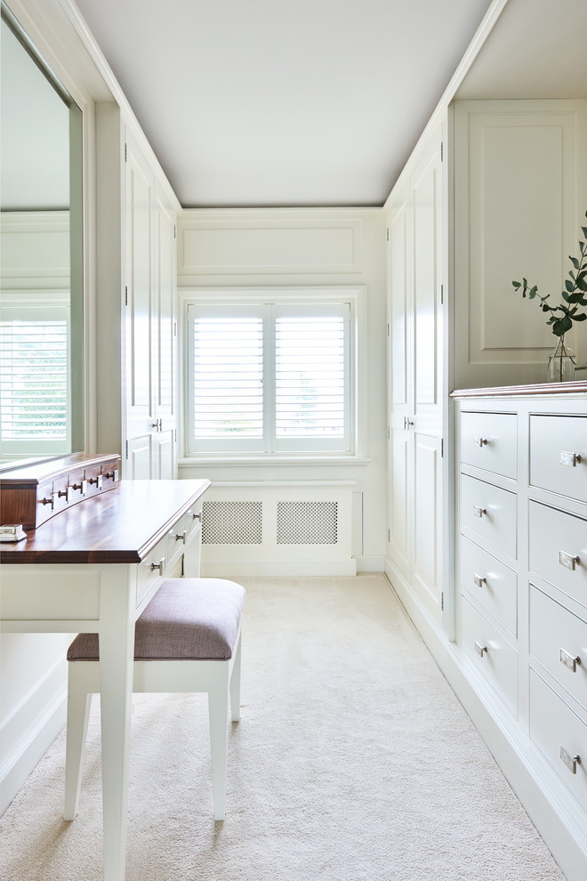 Ejemplo de vestidor unisex campestre de tamaño medio con armarios con paneles con relieve, puertas de armario blancas, moqueta y suelo beige