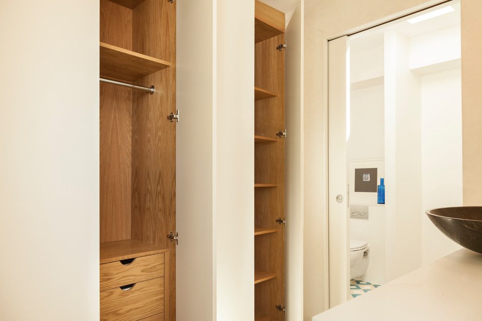 Small contemporary gender neutral dressing room in London with flat-panel cabinets and medium wood cabinets.