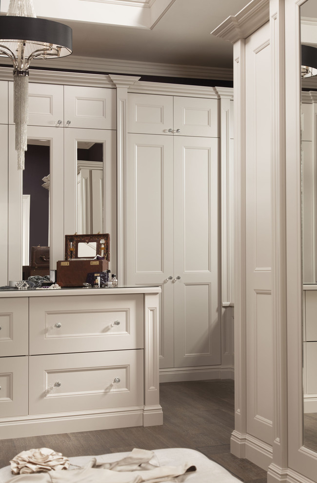 Modelo de armario y vestidor tradicional grande con armarios estilo shaker, puertas de armario blancas, suelo de madera en tonos medios y suelo marrón