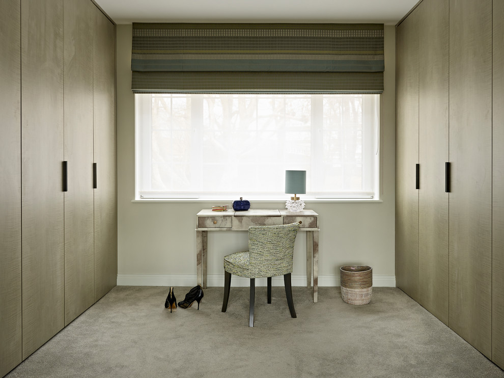 This is an example of a medium sized contemporary dressing room for women in London with carpet, flat-panel cabinets, brown cabinets and grey floors.