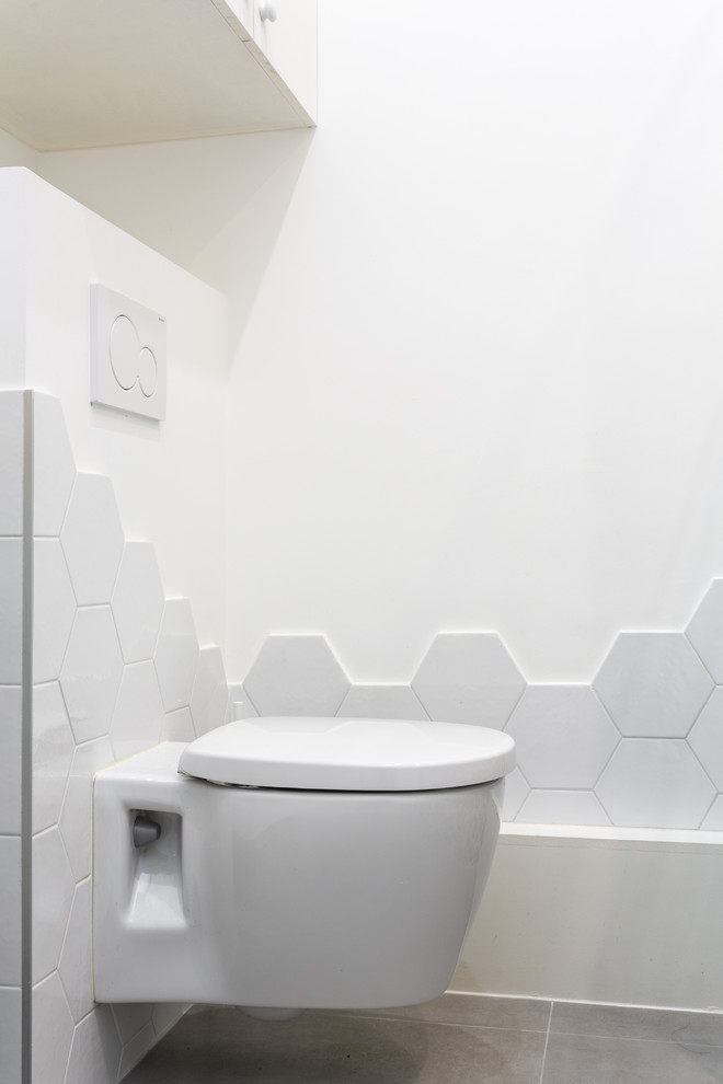 На фото: маленький туалет в современном стиле с инсталляцией, белой плиткой, бетонным полом, серым полом, плоскими фасадами, белыми фасадами, керамической плиткой, белыми стенами и белой столешницей для на участке и в саду с