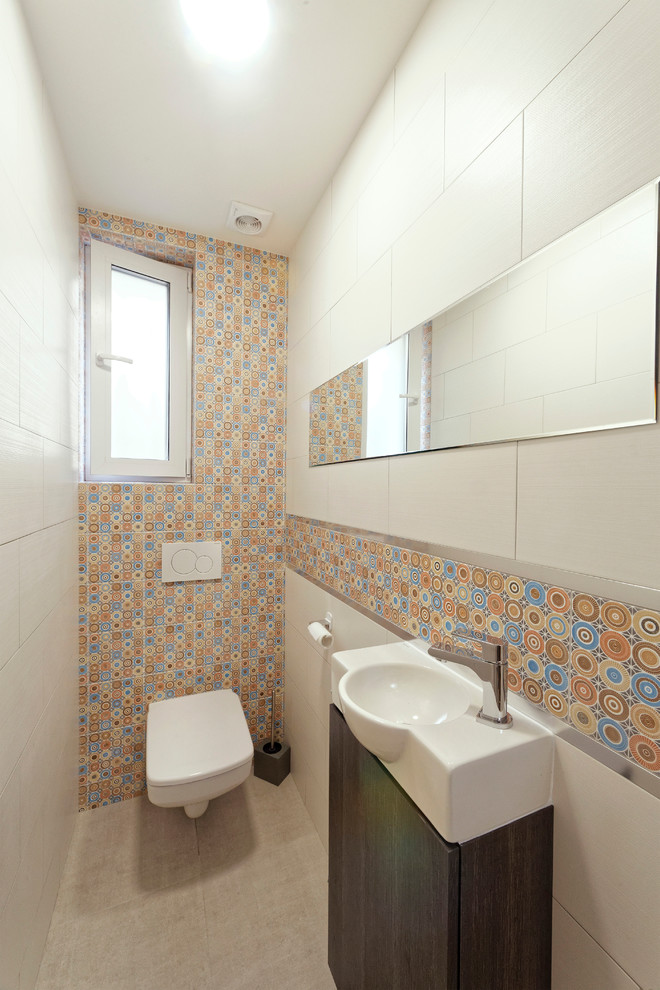 Idee per un piccolo bagno di servizio minimal con WC sospeso, piastrelle multicolore, pareti bianche, pavimento con piastrelle in ceramica, lavabo sospeso e pavimento grigio
