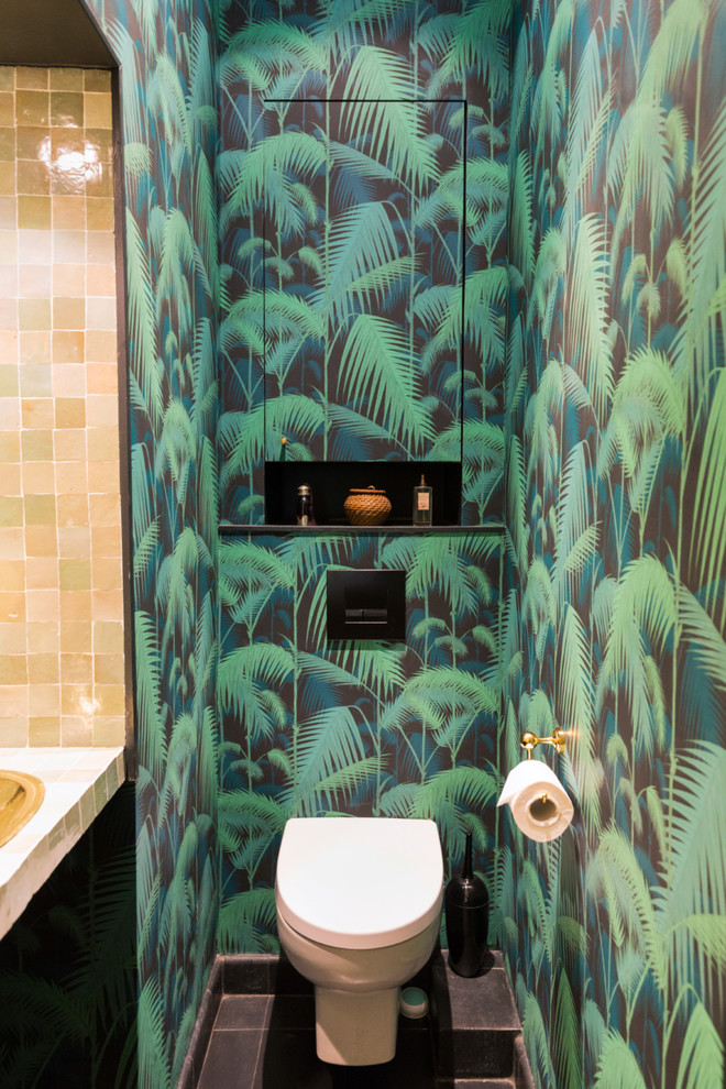 Mittelgroße Moderne Gästetoilette mit offenen Schränken, Toilette mit Aufsatzspülkasten, beigen Fliesen, Mosaikfliesen, grüner Wandfarbe, Zementfliesen für Boden, Aufsatzwaschbecken, schwarzem Boden, beiger Waschtischplatte und Tapetenwänden in Paris