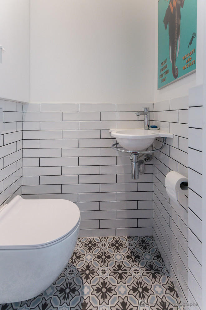 Esempio di un piccolo bagno di servizio minimal con ante a filo, ante bianche, WC sospeso, piastrelle bianche, piastrelle in ceramica, pareti bianche, pavimento con piastrelle in ceramica, lavabo sospeso, pavimento blu e top bianco