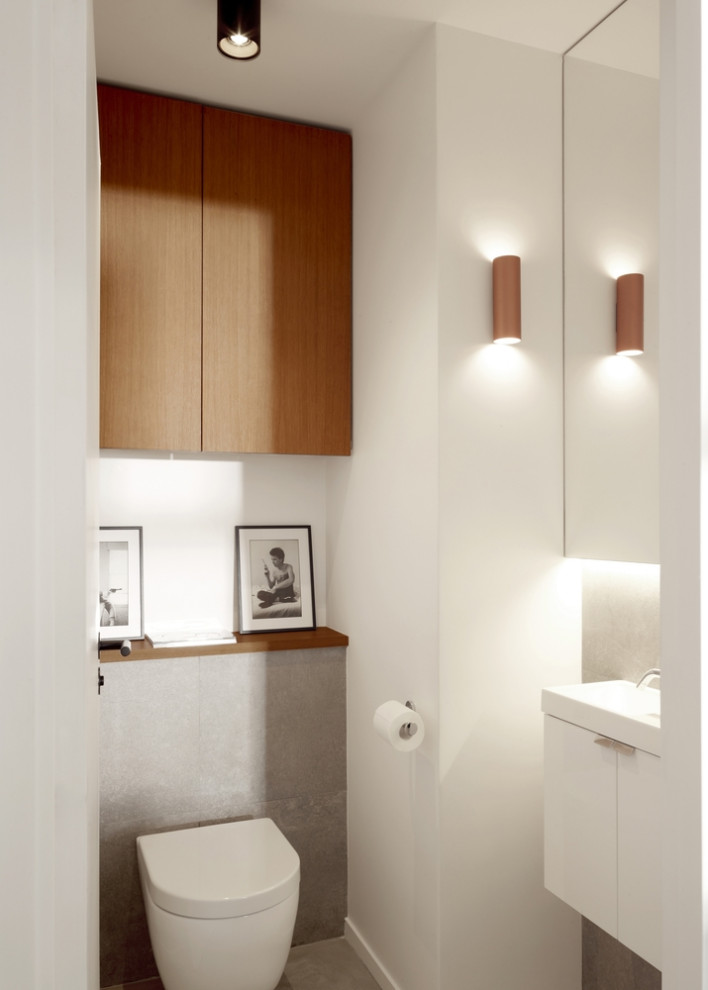 Cette image montre un WC suspendu design avec un placard à porte plane, des portes de placard marrons, un lavabo suspendu, un plan de toilette blanc et meuble-lavabo encastré.