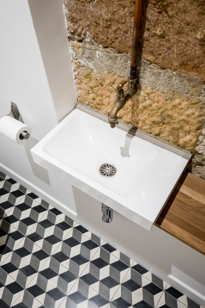 Cette photo montre un WC et toilettes scandinave avec un mur blanc, carreaux de ciment au sol et un sol gris.
