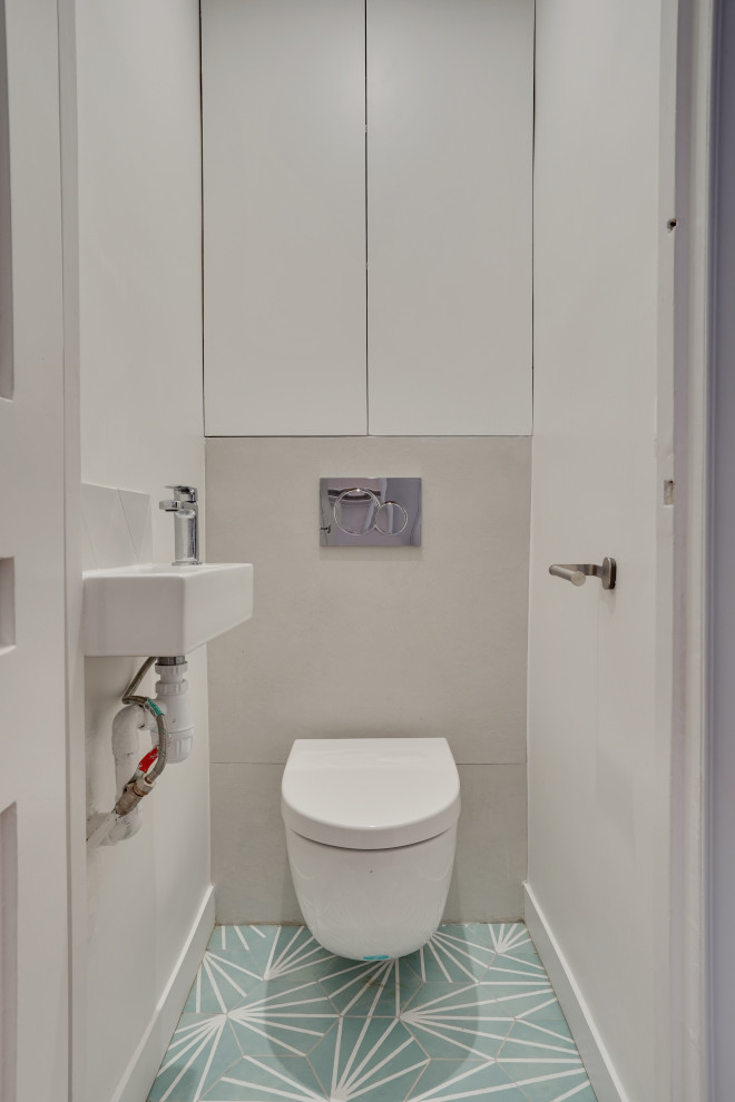 Powder room - small modern gray tile and cement tile green floor and cement tile floor powder room idea in Paris with beaded inset cabinets, white cabinets, a wall-mount toilet and gray walls