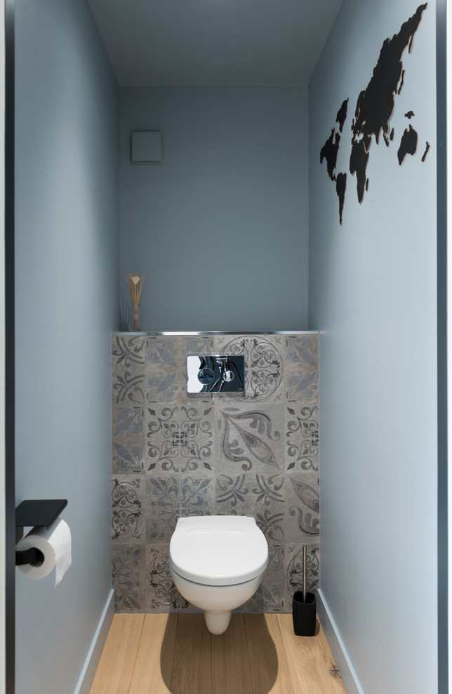 グルノーブルにあるお手頃価格の巨大な北欧スタイルのおしゃれなトイレ・洗面所 (壁掛け式トイレ、セメントタイル、青い壁、淡色無垢フローリング、白い洗面カウンター) の写真