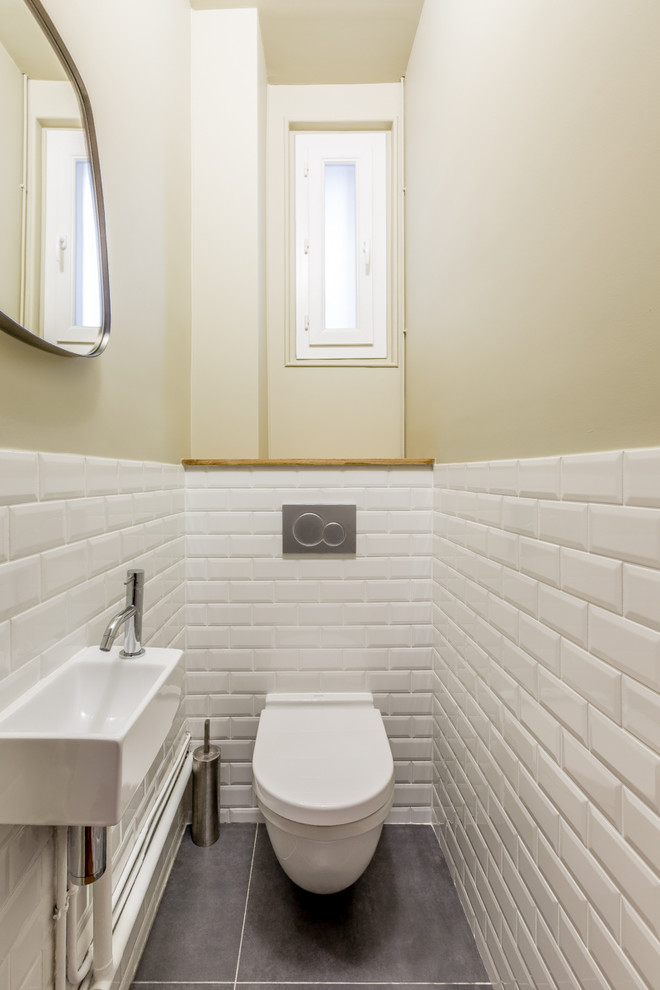 Cette photo montre un petit WC suspendu tendance avec des carreaux de porcelaine, un mur vert, sol en béton ciré, un lavabo suspendu et un sol gris.