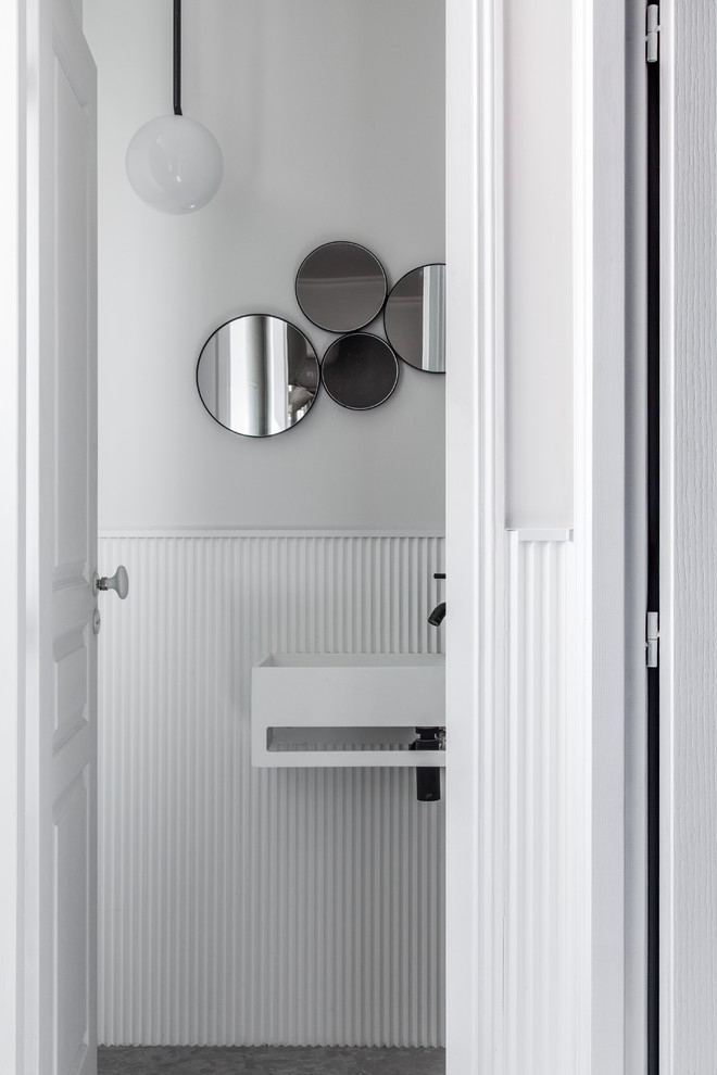 Idéer för att renovera ett mellanstort skandinaviskt toalett, med vit kakel, vita väggar, ett väggmonterat handfat, grått golv, vita skåp, en vägghängd toalettstol och klinkergolv i keramik