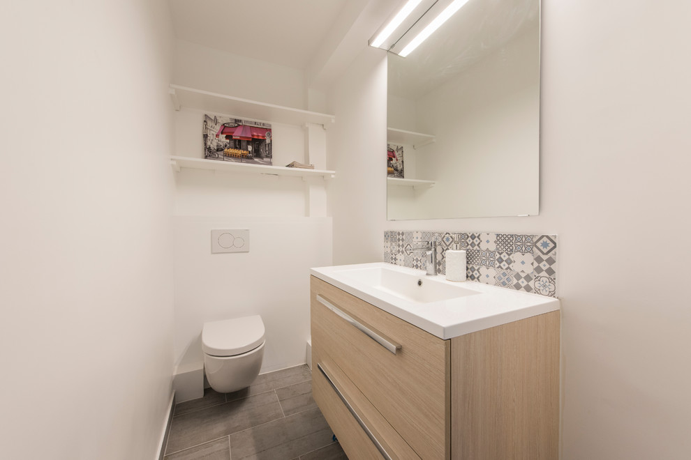 Inspiration pour un petit WC suspendu design avec un carrelage blanc, des carreaux de céramique, un mur blanc, carreaux de ciment au sol, une vasque, un sol gris et un plan de toilette blanc.