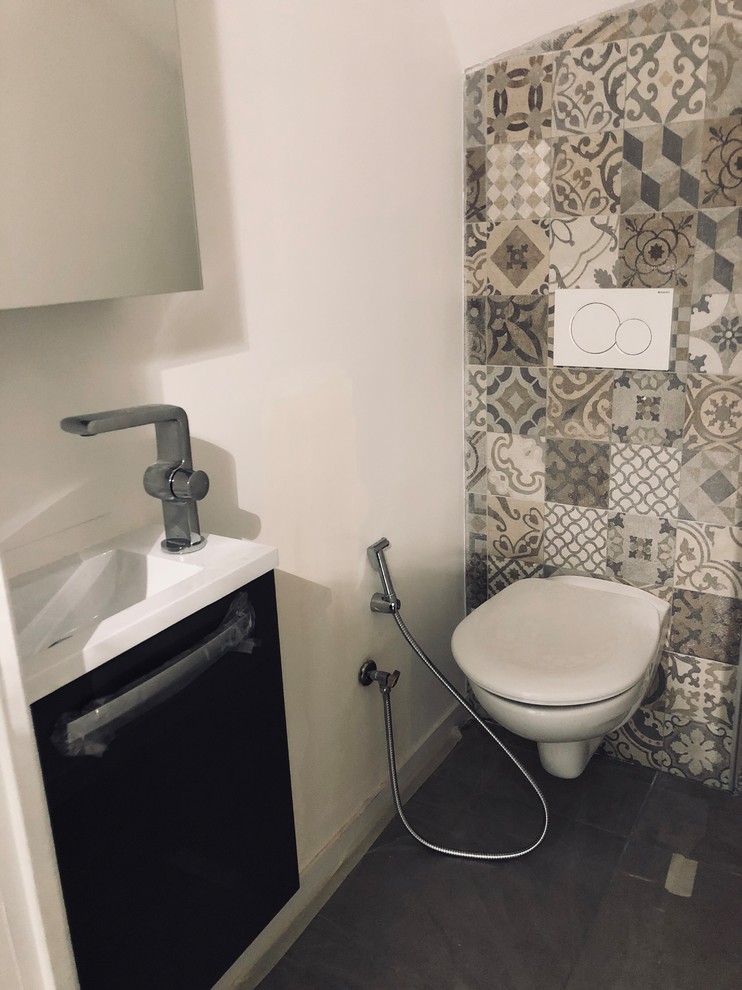 Modern inredning av ett litet vit vitt toalett, med luckor med profilerade fronter, svarta skåp, en toalettstol med hel cisternkåpa, beige kakel, keramikplattor, beige väggar, klinkergolv i keramik, ett väggmonterat handfat och grått golv