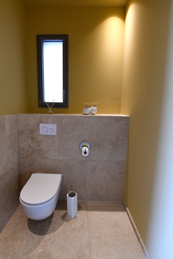Exemple d'un petit WC suspendu méditerranéen avec un carrelage beige, des carreaux de céramique, un mur jaune, un sol en carrelage de céramique, un plan de toilette en surface solide, un sol beige et un plan de toilette beige.