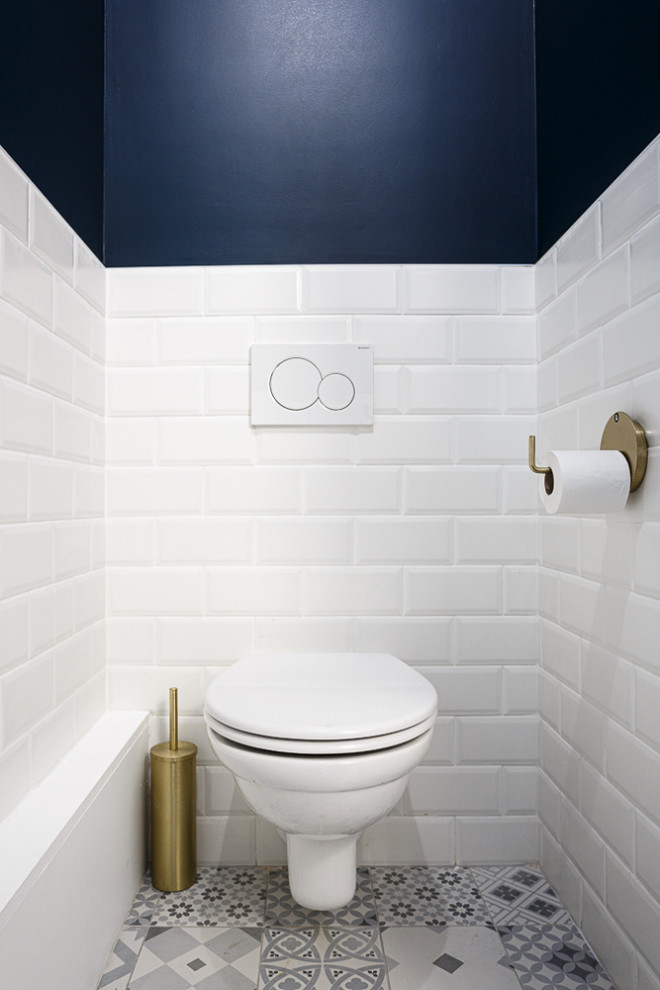 Inspiration för ett mellanstort funkis vit vitt toalett, med släta luckor, blå skåp, en vägghängd toalettstol, vit kakel, keramikplattor, blå väggar, klinkergolv i keramik, ett väggmonterat handfat, bänkskiva i akrylsten och vitt golv