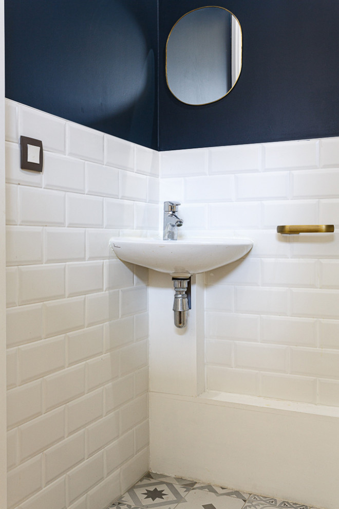This is an example of a medium sized modern cloakroom in Paris with flat-panel cabinets, blue cabinets, a wall mounted toilet, white tiles, ceramic tiles, blue walls, ceramic flooring, a wall-mounted sink, solid surface worktops, white floors, white worktops and a floating vanity unit.