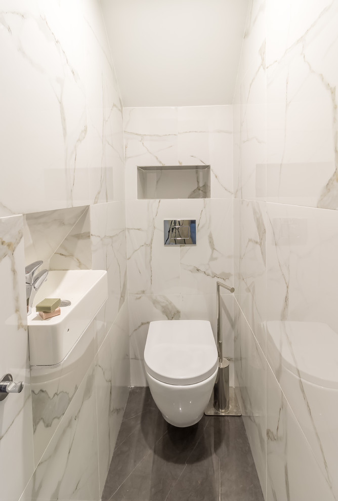 Esempio di un piccolo bagno di servizio design con WC sospeso, piastrelle bianche, piastrelle in ceramica, pareti bianche, pavimento in gres porcellanato, lavabo sospeso, top piastrellato, pavimento grigio e top grigio