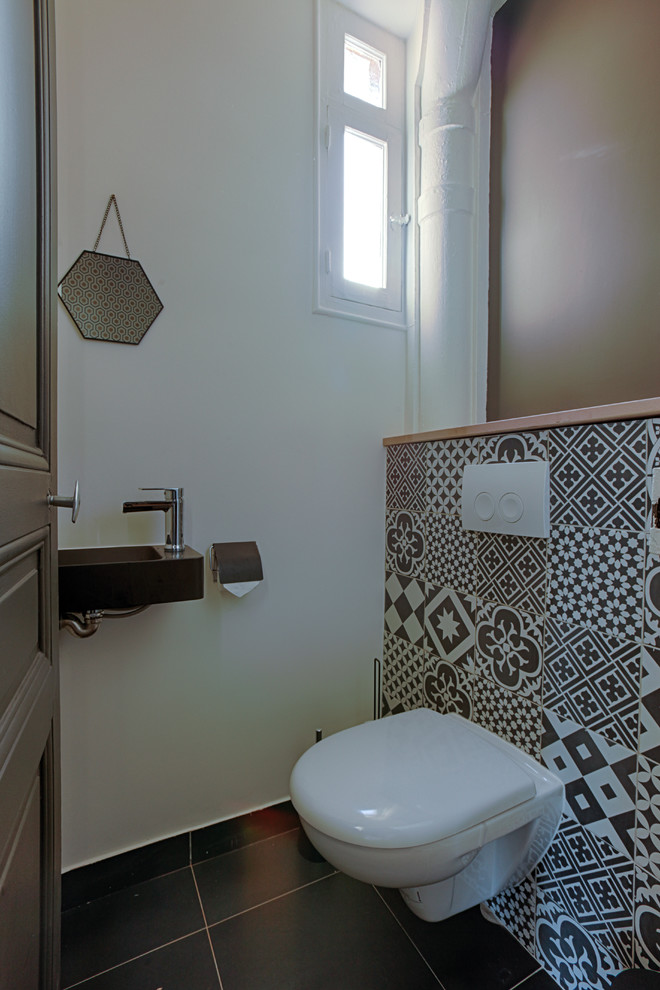 Foto de aseo industrial pequeño con sanitario de pared, baldosas y/o azulejos de cemento, paredes blancas, lavabo suspendido y suelo negro