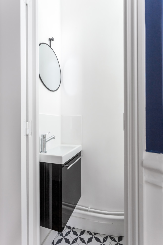 Small traditional cloakroom in Paris with beaded cabinets, black cabinets, a wall mounted toilet, white tiles, ceramic tiles, white walls, cement flooring, a console sink, tiled worktops, black floors and black worktops.