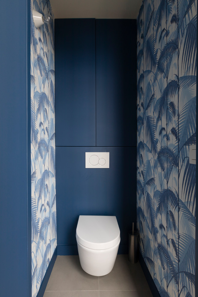 パリにあるお手頃価格の小さなコンテンポラリースタイルのおしゃれなトイレ・洗面所 (シェーカースタイル扉のキャビネット、青いキャビネット、壁掛け式トイレ、青い壁、ベージュの床) の写真