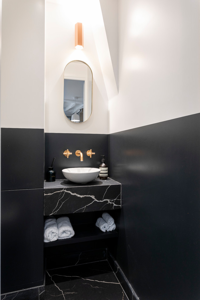 Moderne Gästetoilette mit offenen Schränken, schwarzen Schränken, bunten Wänden, Aufsatzwaschbecken, schwarzem Boden und schwarzer Waschtischplatte in Paris