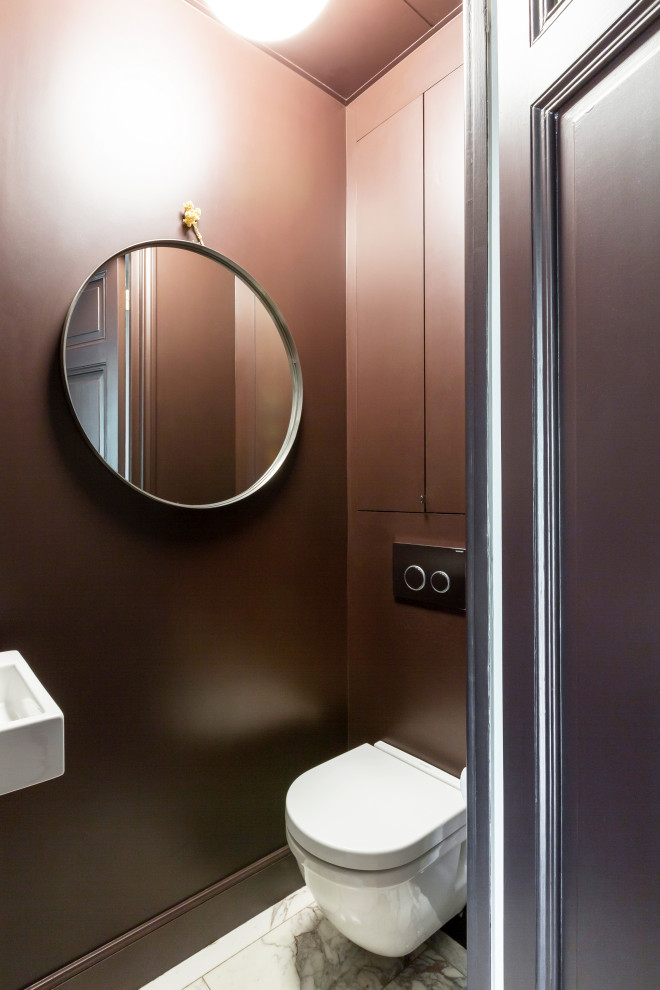 Cette photo montre un petit WC suspendu tendance avec un placard à porte affleurante, des portes de placard marrons, un mur marron, un sol en marbre, un lavabo suspendu, un sol blanc et meuble-lavabo encastré.