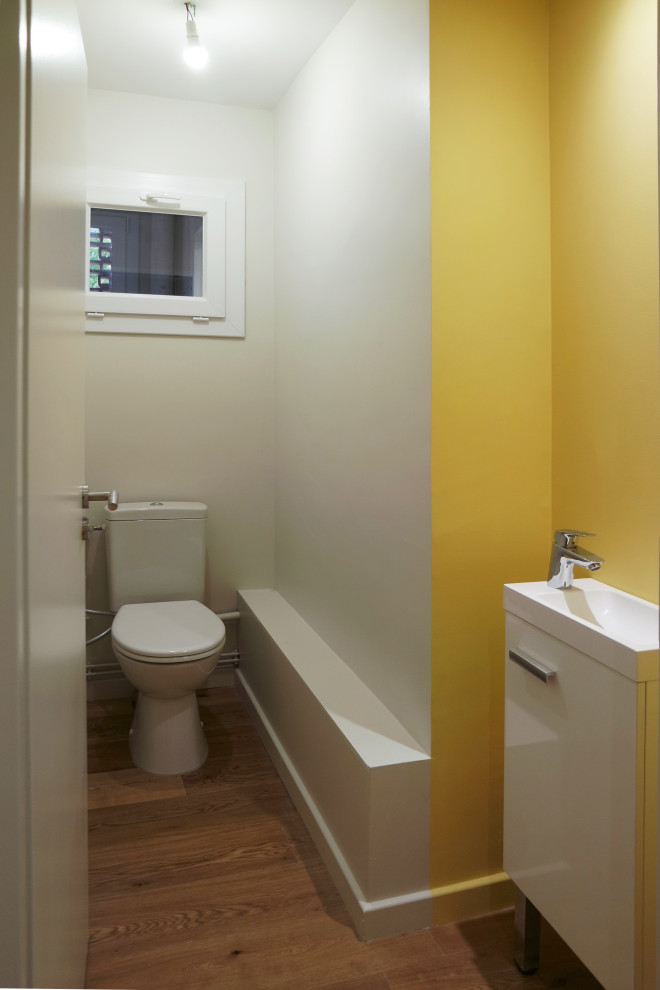Aménagement d'un WC et toilettes scandinave avec un mur jaune et un sol en bois brun.