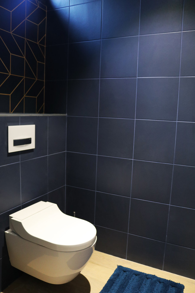 Réalisation d'un WC suspendu design de taille moyenne avec un carrelage bleu, des carreaux de céramique, un mur orange, parquet clair, un plan de toilette en carrelage, un sol marron et un plan de toilette bleu.