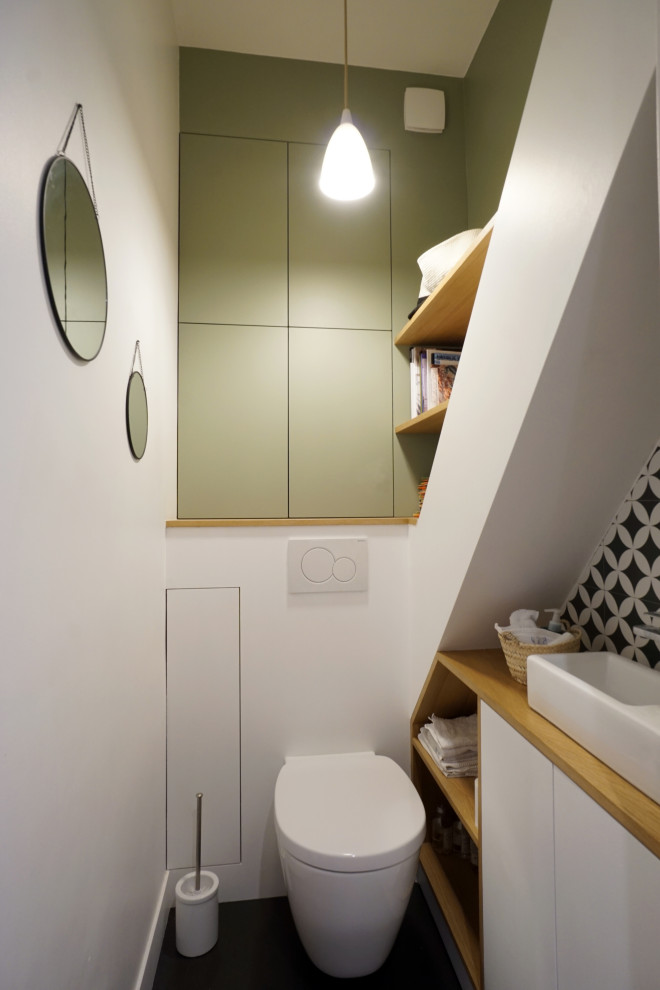 Inredning av ett modernt litet beige beige toalett, med släta luckor, vita skåp, en vägghängd toalettstol, svart och vit kakel, vita väggar, ett fristående handfat, träbänkskiva och svart golv