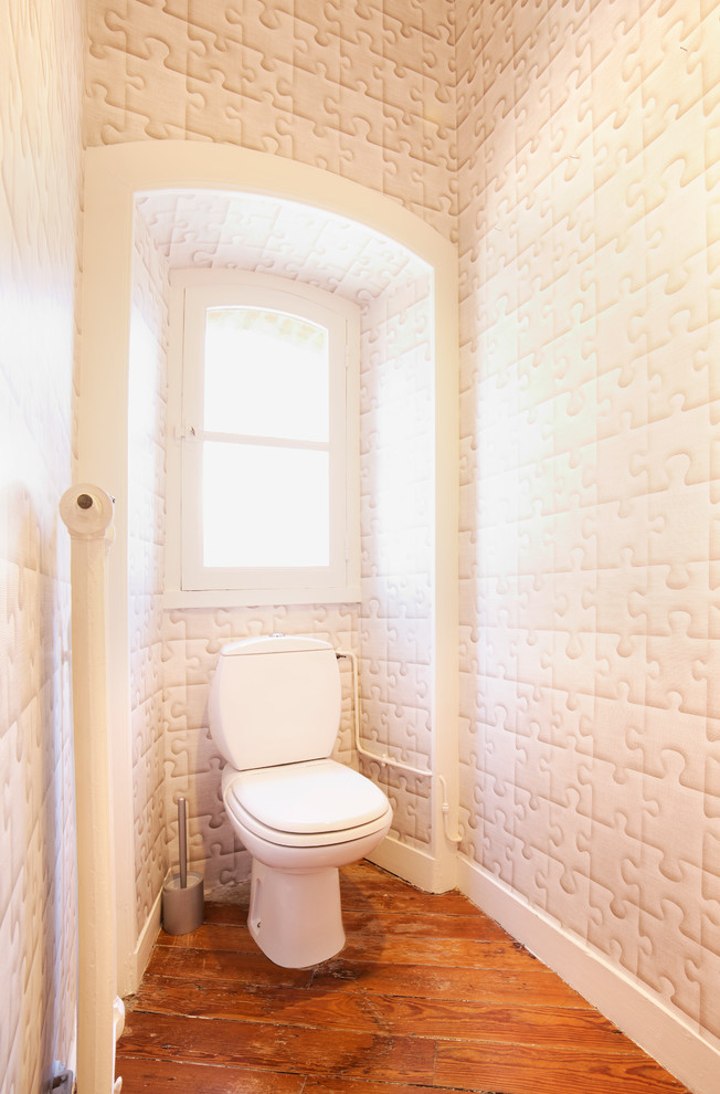 Inredning av ett klassiskt mellanstort toalett, med en toalettstol med separat cisternkåpa, vita väggar, mellanmörkt trägolv och beiget golv