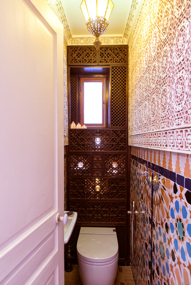 Пример оригинального дизайна: маленький туалет в средиземноморском стиле с коричневыми фасадами, унитазом-моноблоком, разноцветной плиткой, терракотовой плиткой, разноцветными стенами и подвесной раковиной для на участке и в саду