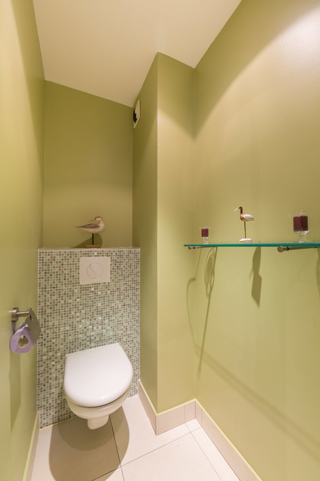 Foto di un bagno di servizio minimal con WC sospeso, piastrelle a mosaico, pareti verdi e pavimento con piastrelle in ceramica