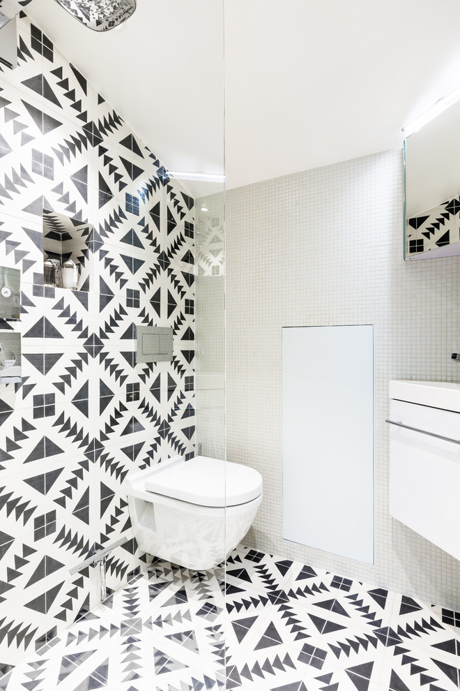 Modern inredning av ett litet vit vitt toalett, med luckor med profilerade fronter, vita skåp, en vägghängd toalettstol, vit kakel, mosaik, vita väggar, cementgolv, ett konsol handfat, kaklad bänkskiva och svart golv