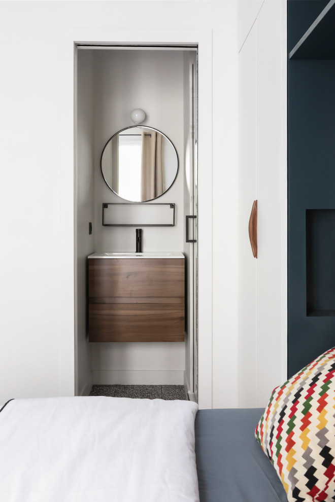 Kleine Moderne Gästetoilette mit flächenbündigen Schrankfronten, hellbraunen Holzschränken, weißer Wandfarbe, integriertem Waschbecken, grauem Boden und weißer Waschtischplatte in Paris