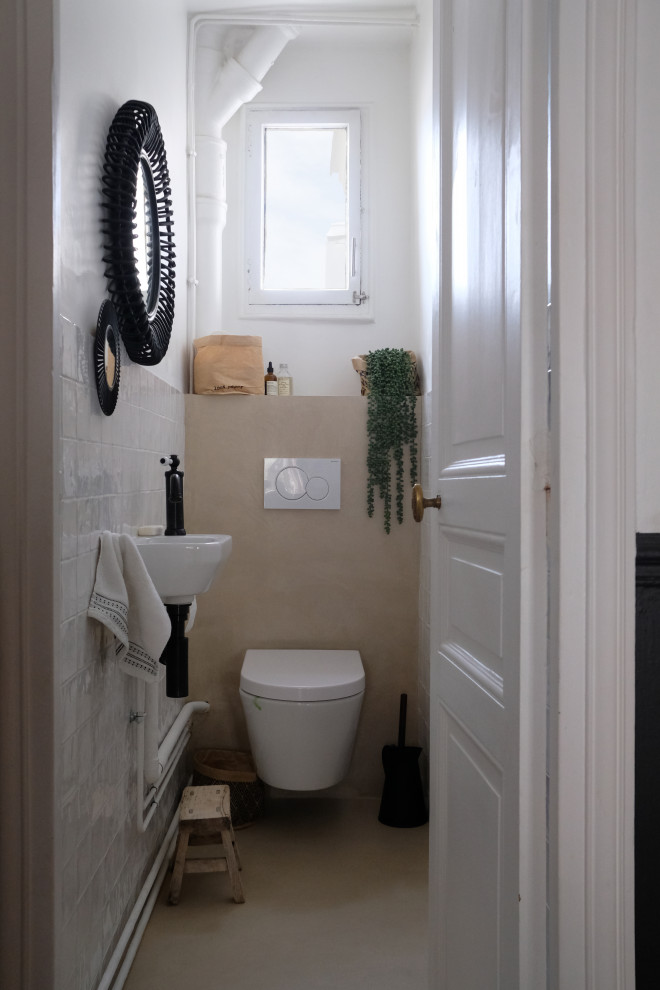 This is an example of a small traditional cloakroom in Paris with a wall mounted toilet, white tiles, ceramic tiles, a wall-mounted sink, beige floors, white walls, concrete flooring and white worktops.
