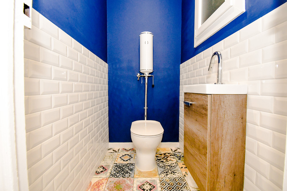 Kleine Mid-Century Gästetoilette mit Toilette mit Aufsatzspülkasten, weißen Fliesen, Porzellanfliesen, blauer Wandfarbe, Zementfliesen für Boden und Wandwaschbecken in Sonstige