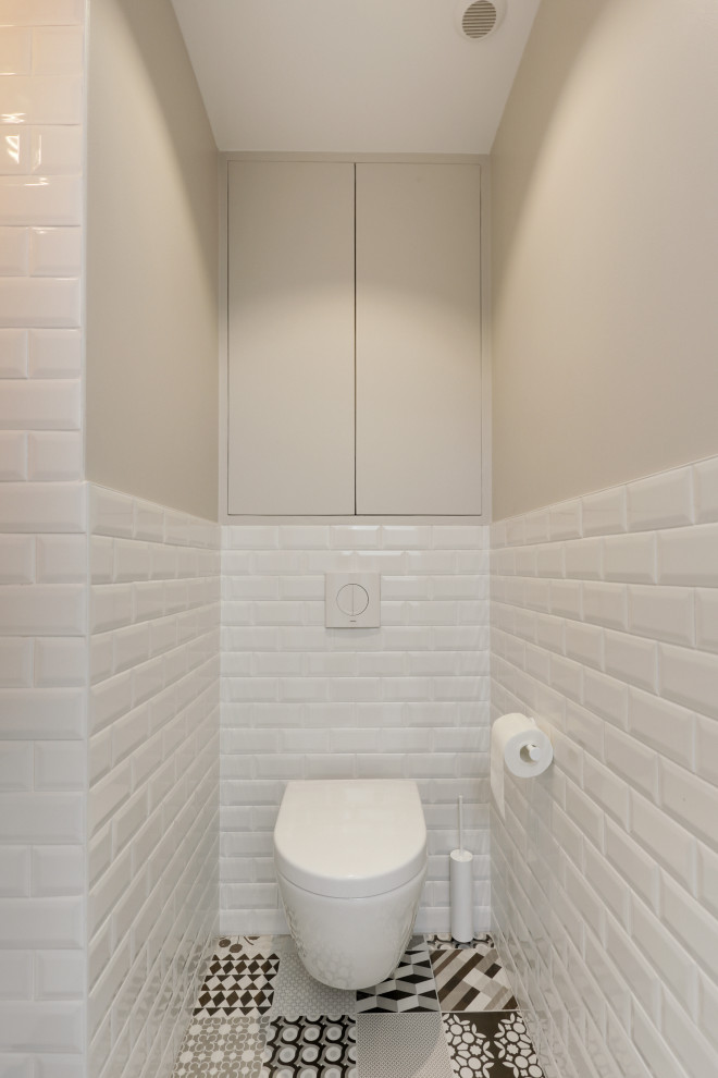 Réalisation d'un WC suspendu design de taille moyenne avec un carrelage blanc, un carrelage métro, un mur beige, un sol en carrelage de céramique, un lavabo suspendu, un sol multicolore et un plan de toilette beige.
